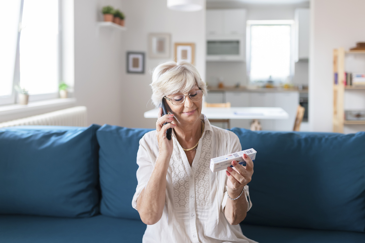 Elderly woman on phone holding medicine